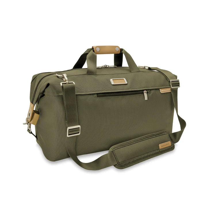 A green Briggs & Riley Baseline Weekender Duffle bag with a main compartment and multiple pockets, featuring a leather nameplate, zipper closures, and a shoulder strap.