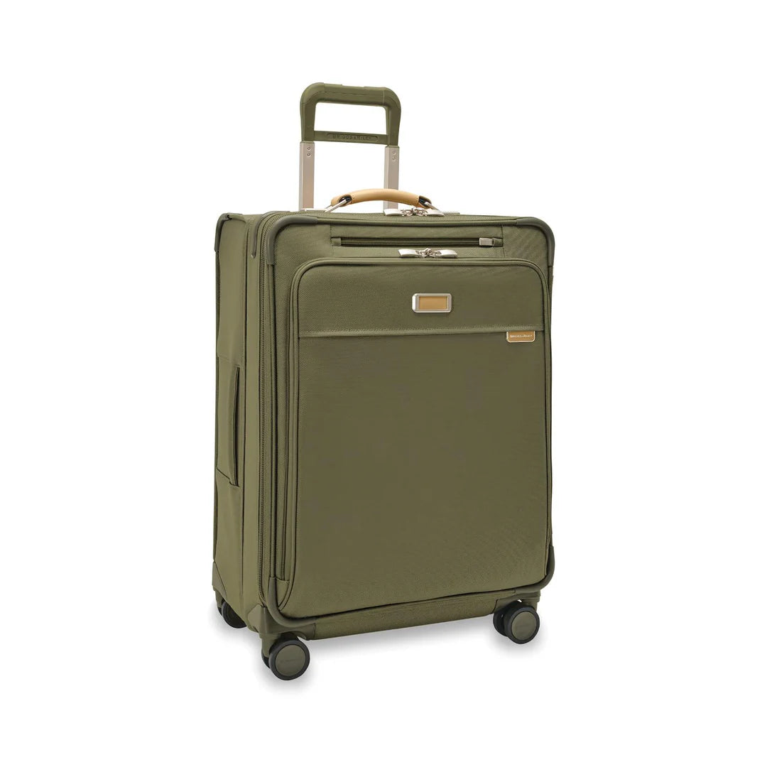 A medium-sized Briggs & Riley Baseline Expandable Spinner suitcase in purple color with telescopic handle, top and side grab handles, and four wheels.